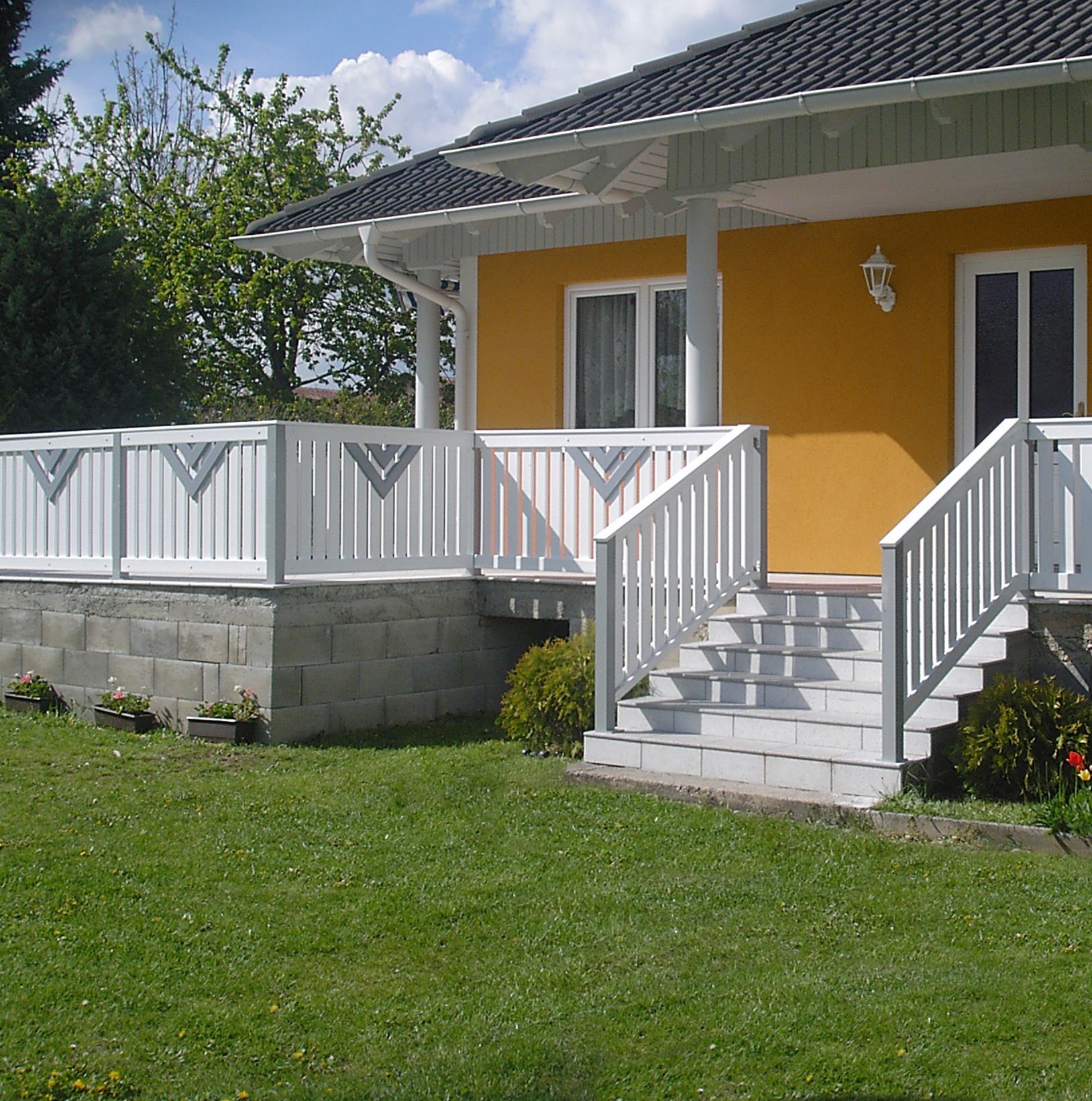 Ein gelbes Haus mit einem weißen Geländer und Stufen.