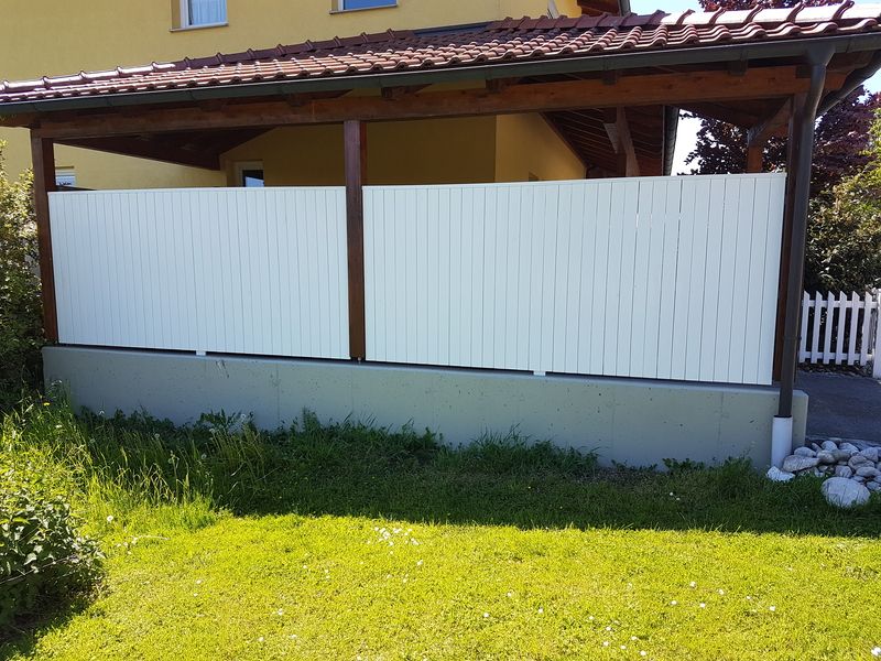Ein weißer Kunststoffsichtschutz vor einer Terrasse